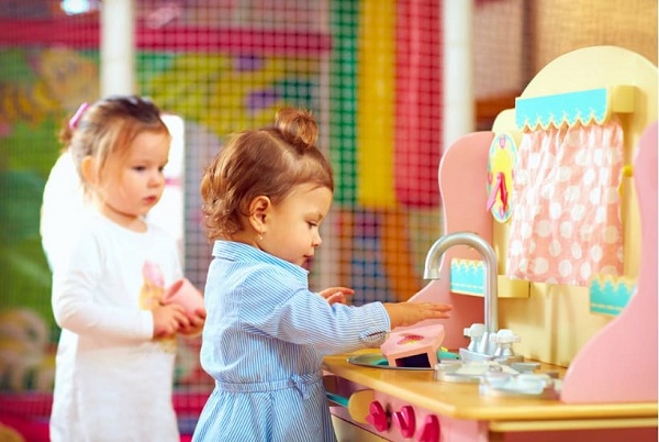 Two girls playing with a kitchen playset
